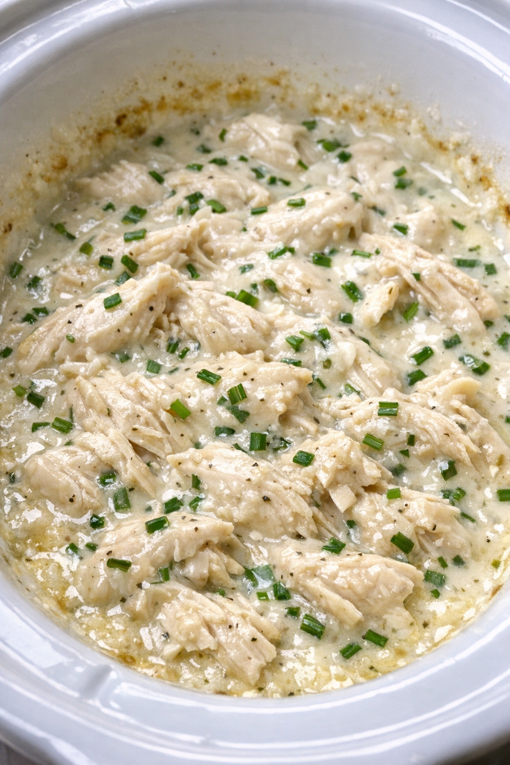 Creamy chive chicken in a white slow cooker