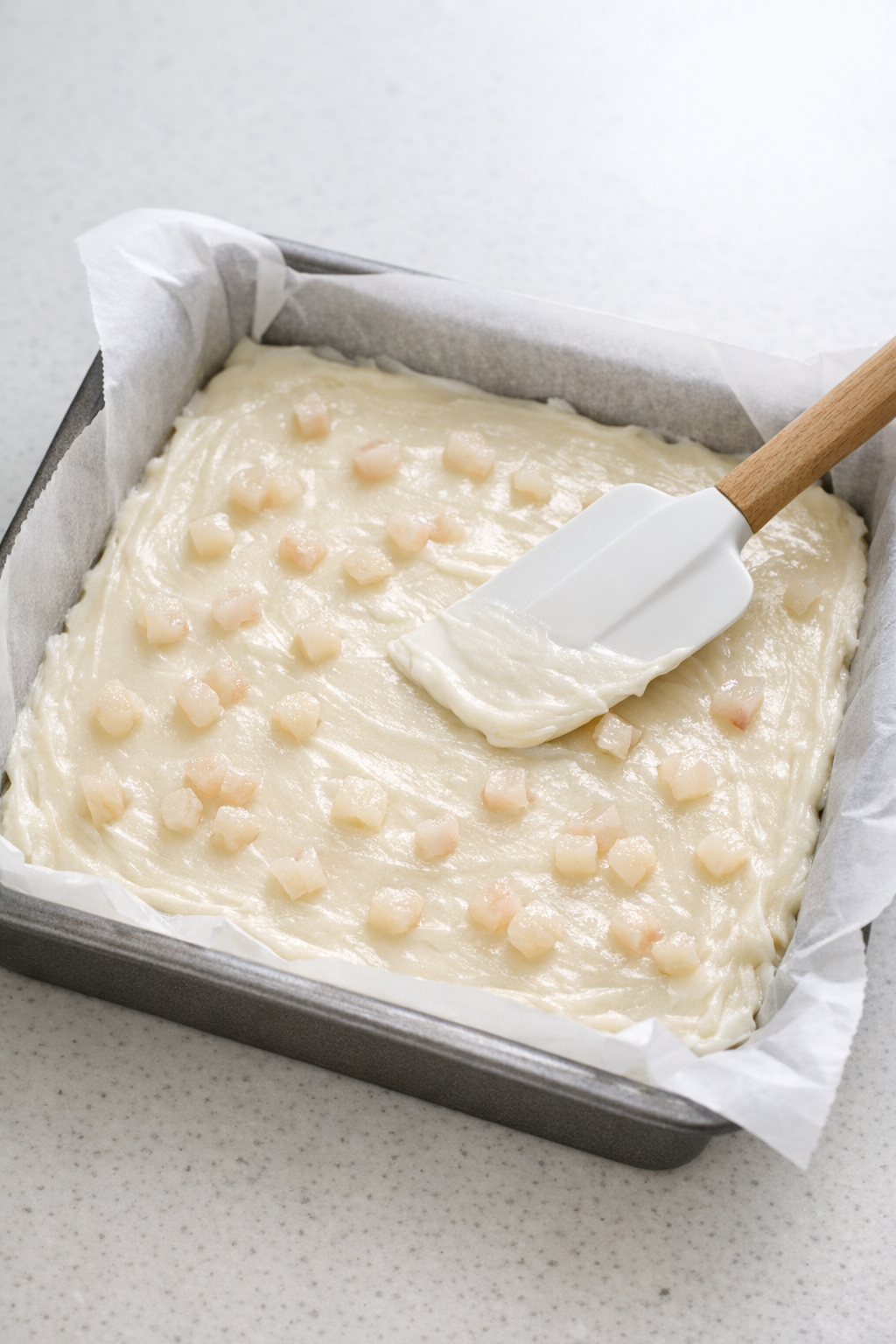 Lychee fudge mixture spread into a parchment-lined pan