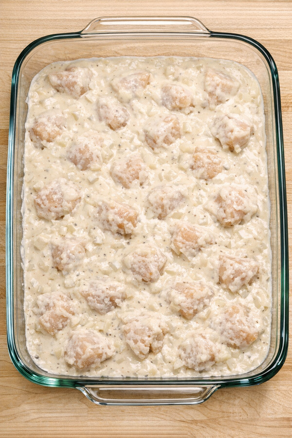 Chicken covered with creamy sauce before baking