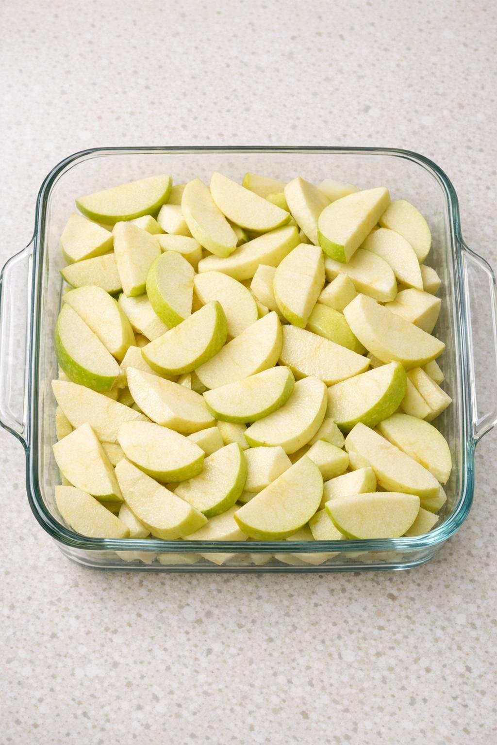 Sliced apples spread in a glass baking dish