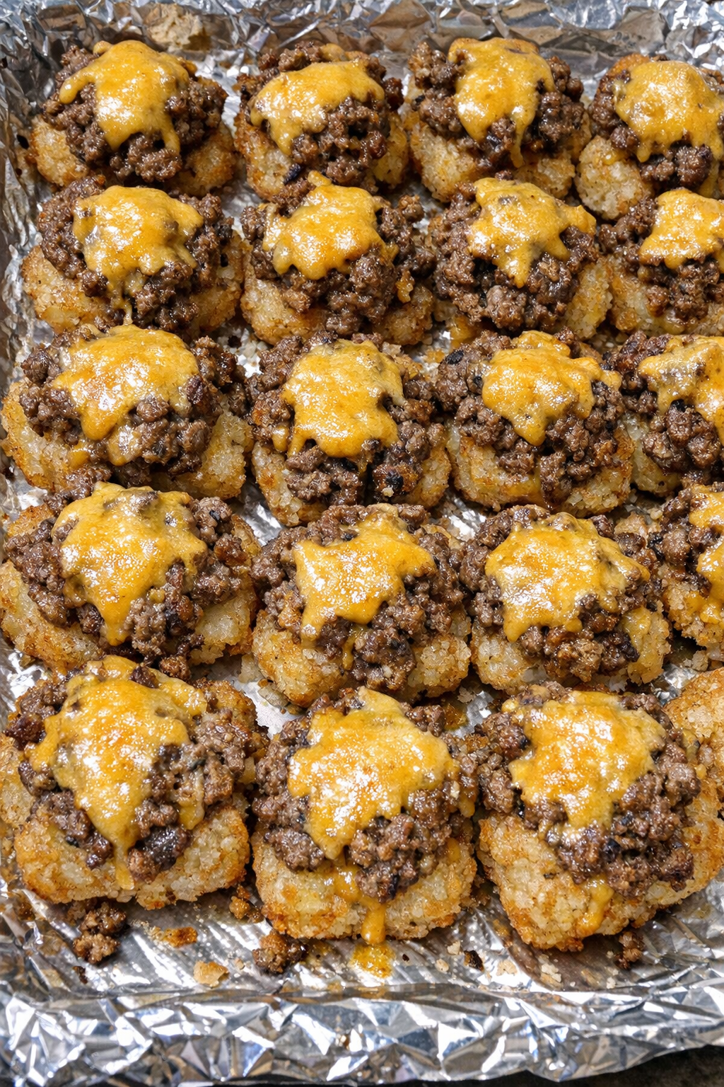 Oven baked beef tater tot bites on a foil-lined baking sheet