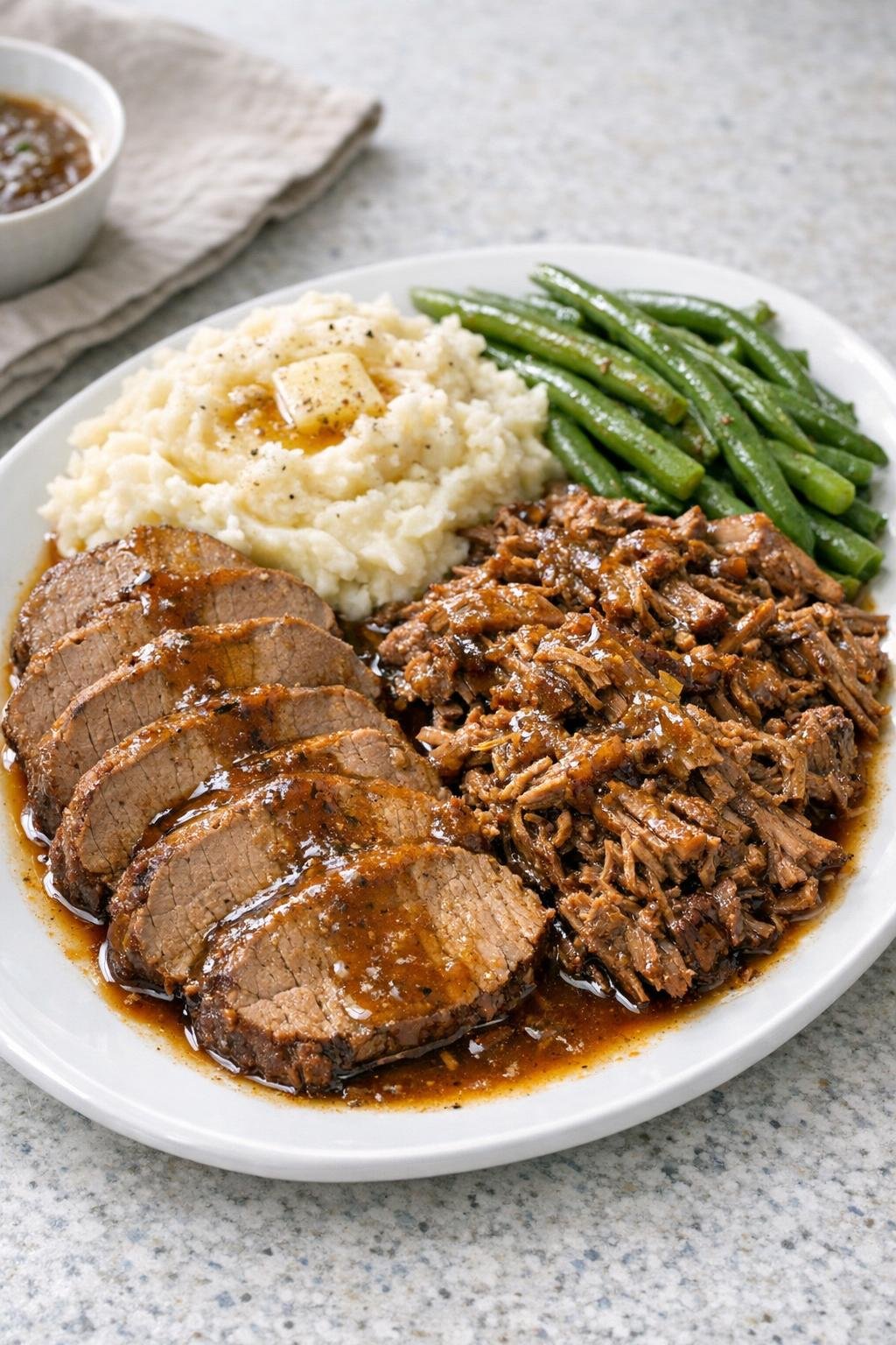 Finished sliced and shredded beef eye of round with cooking juices on a platter