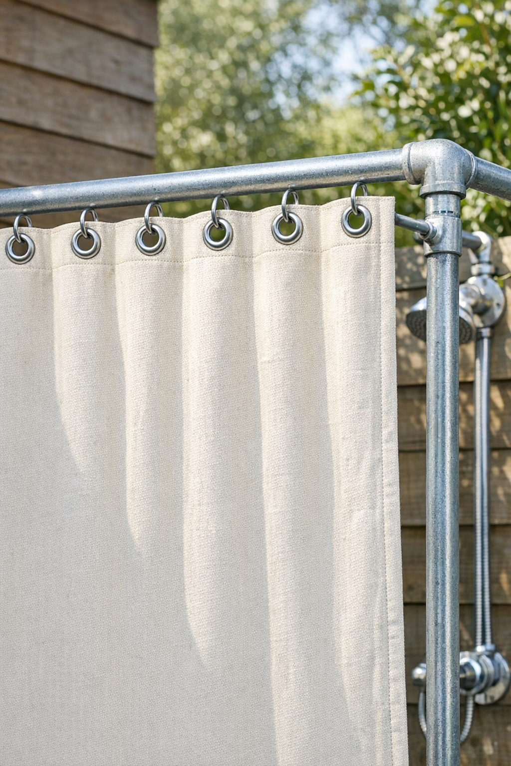 Finished natural canvas outdoor shower curtain hanging from a galvanized pipe frame