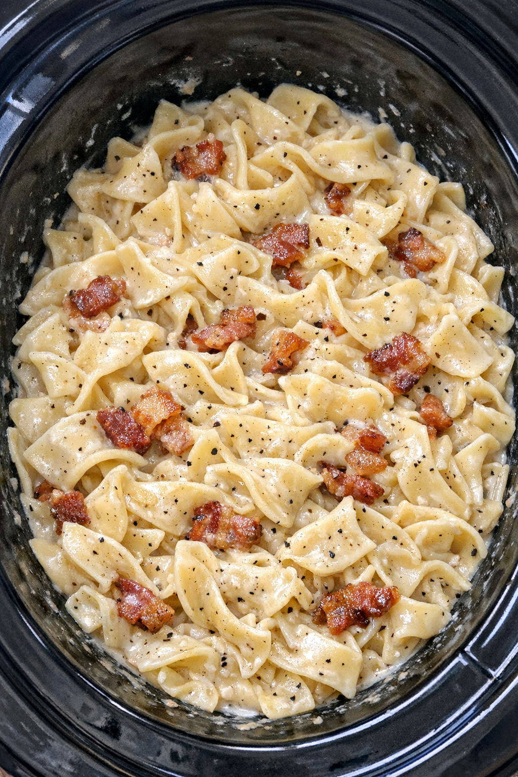 Slow cooker Amish bacon cream noodles in a black slow cooker
