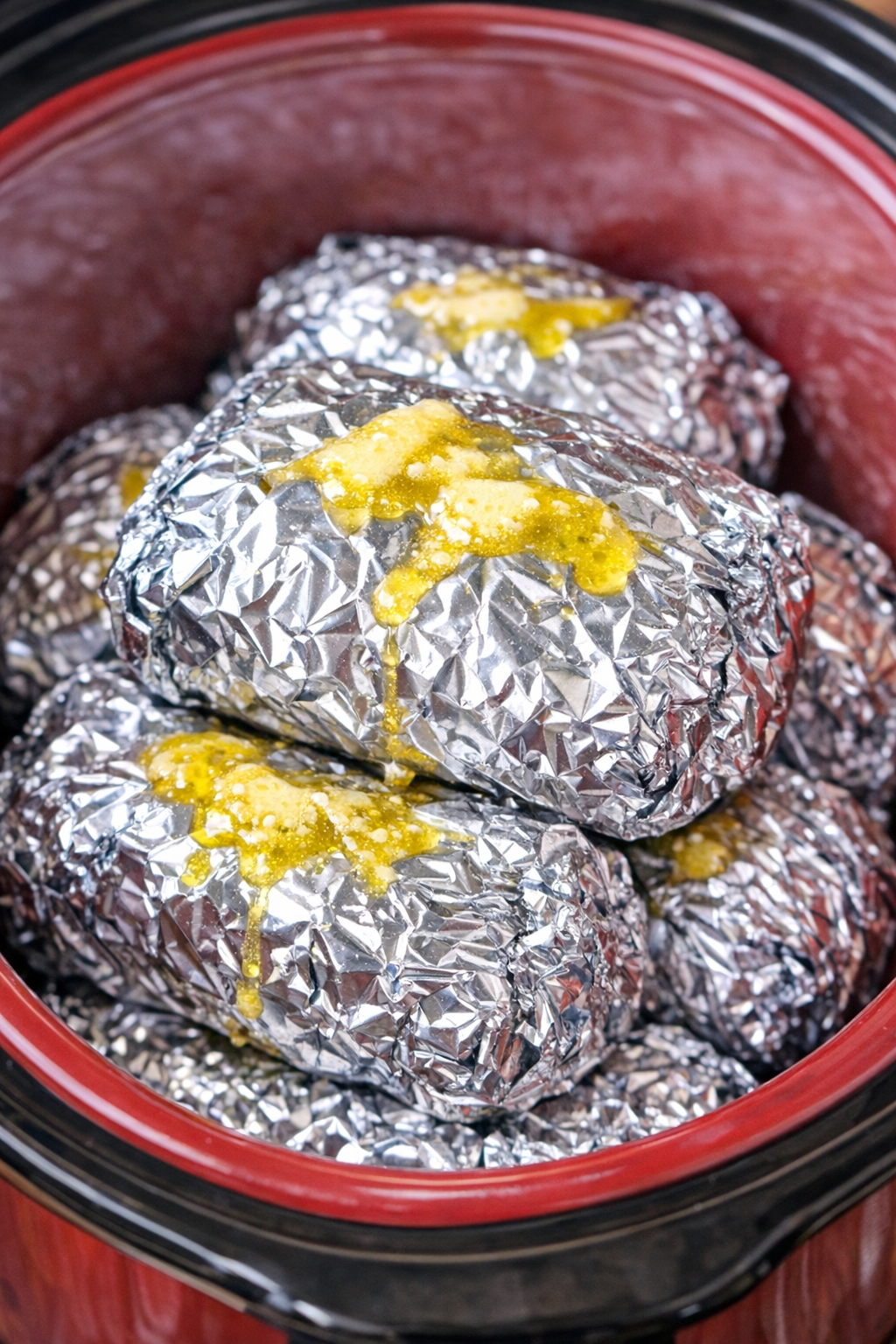 Slow cooker beef and green chili foil packets in a red slow cooker