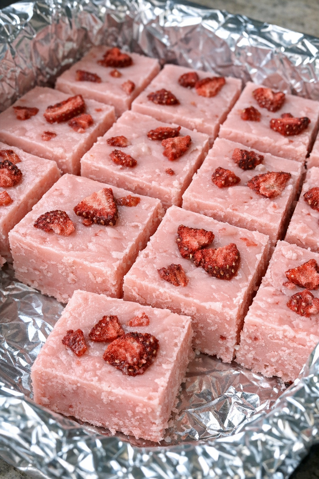 Slow cooker pink drink fudge squares in a foil-lined pan