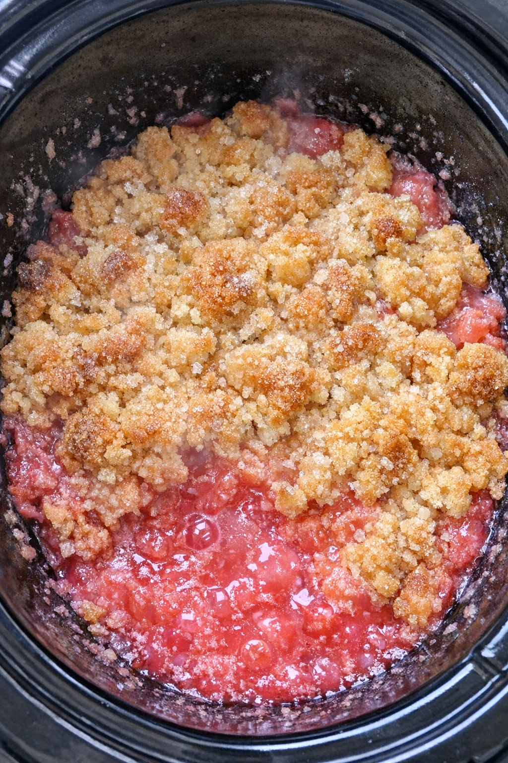 Slow cooker pink senorita dump cake in a black slow cooker