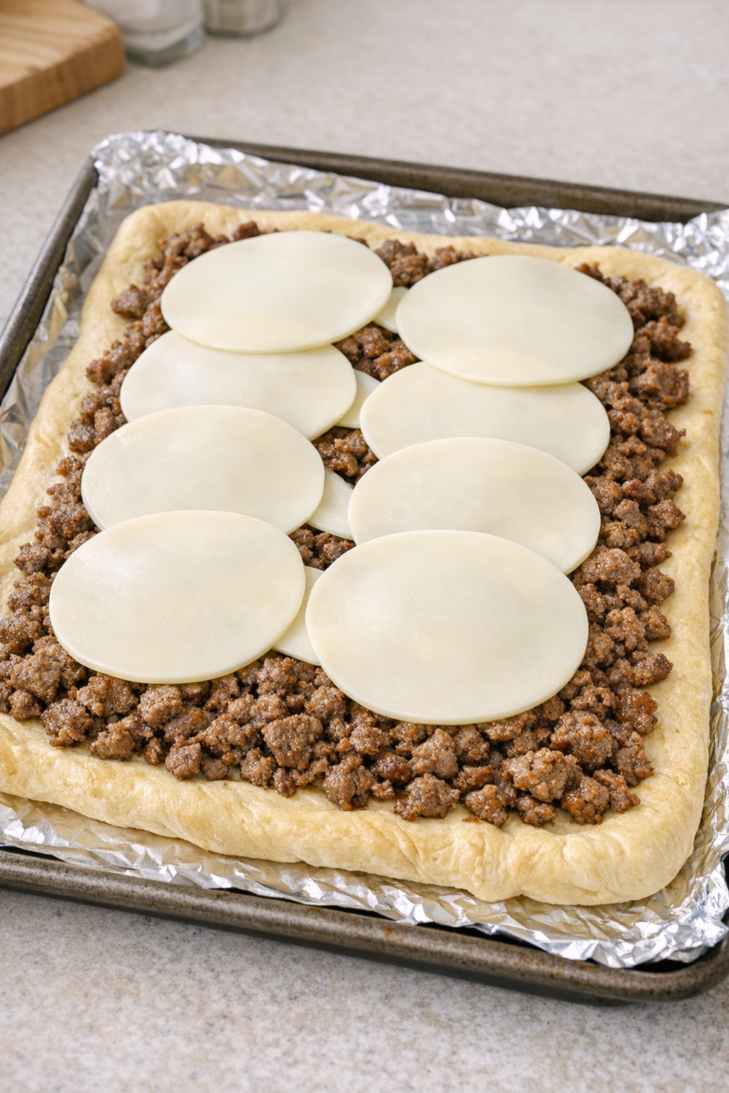 Flatbread assembled with beef and provolone before baking