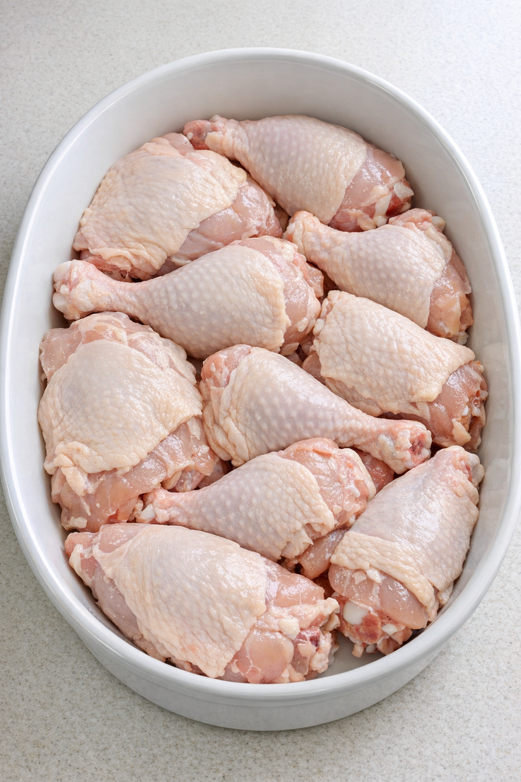 Raw chicken arranged in baking dish