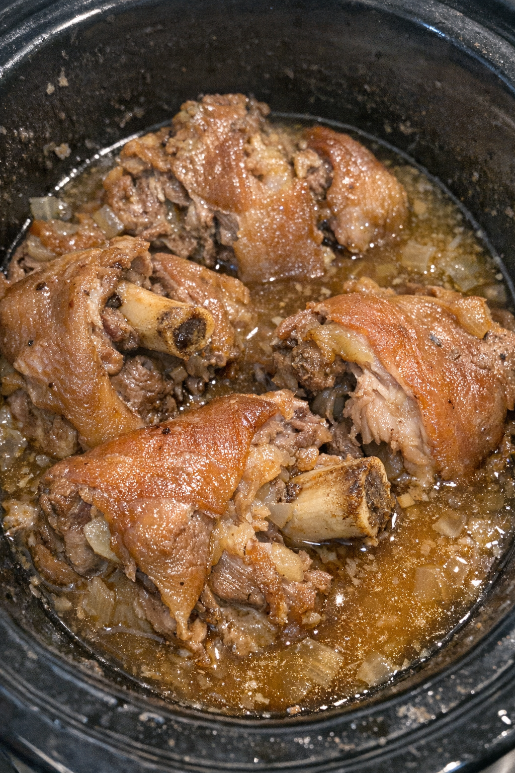 Tender pork hocks in savory broth in a slow cooker