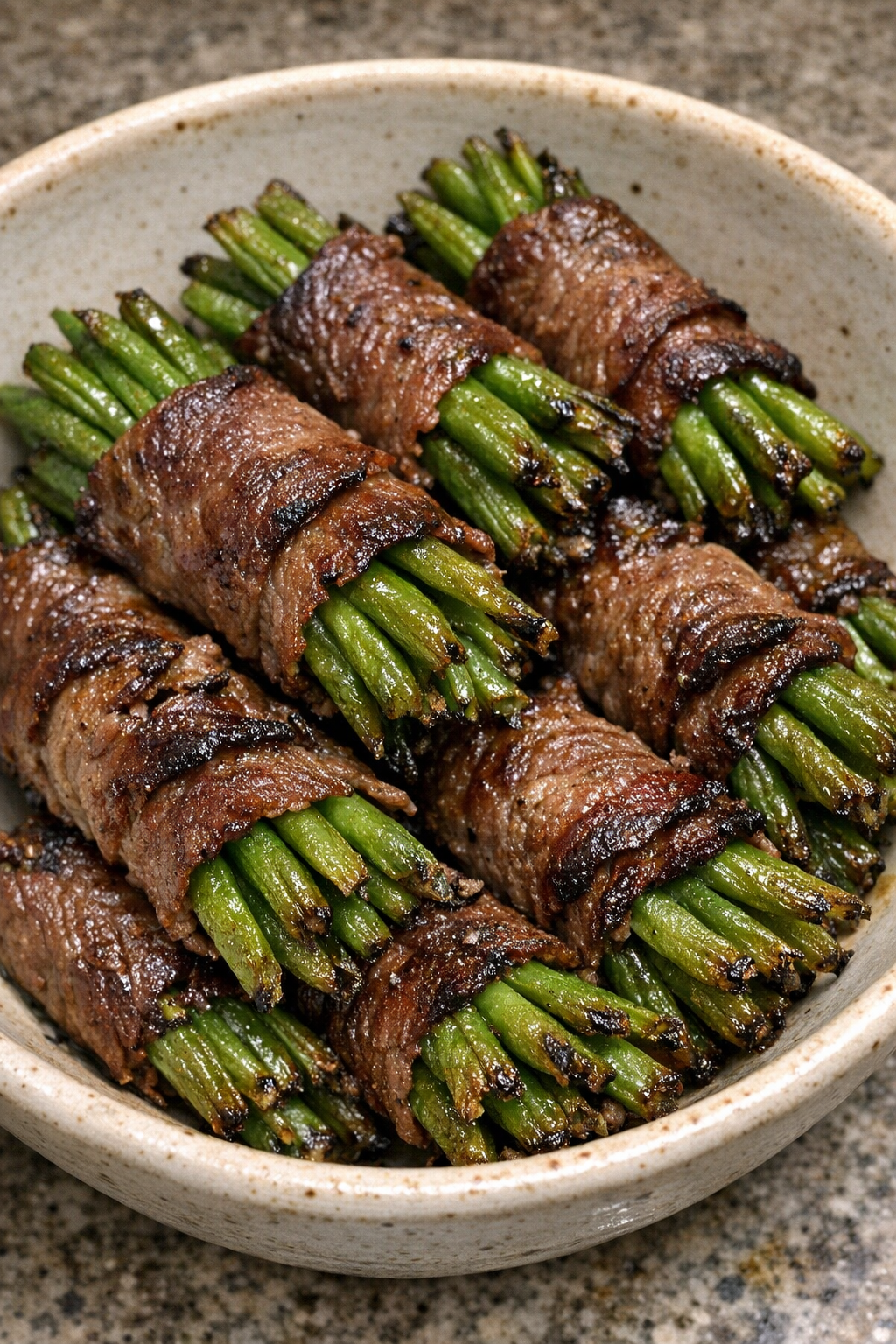 Oven baked beef wrapped green bean bundles in a ceramic bowl