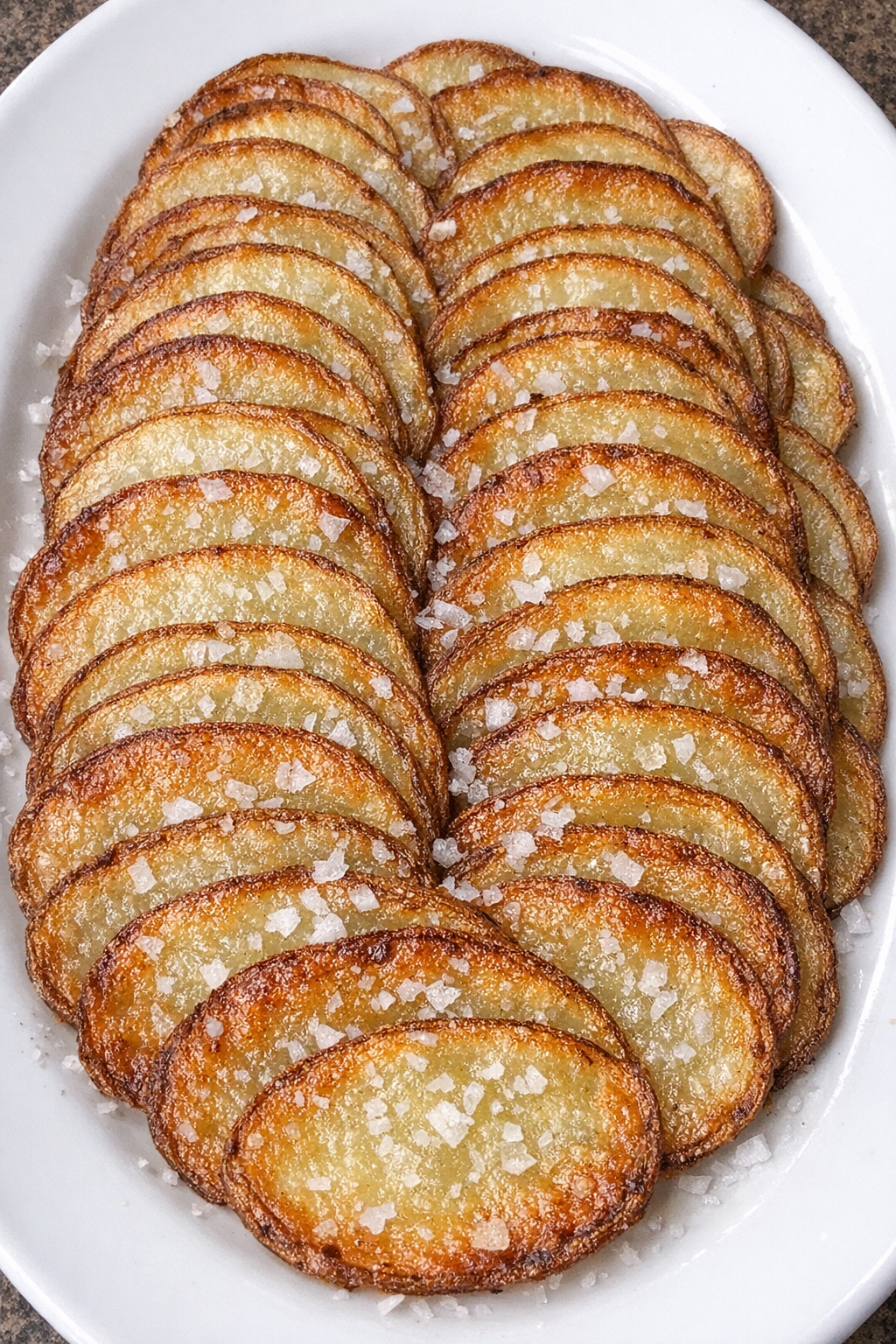 Crispy golden potato shingles on a white oval platter