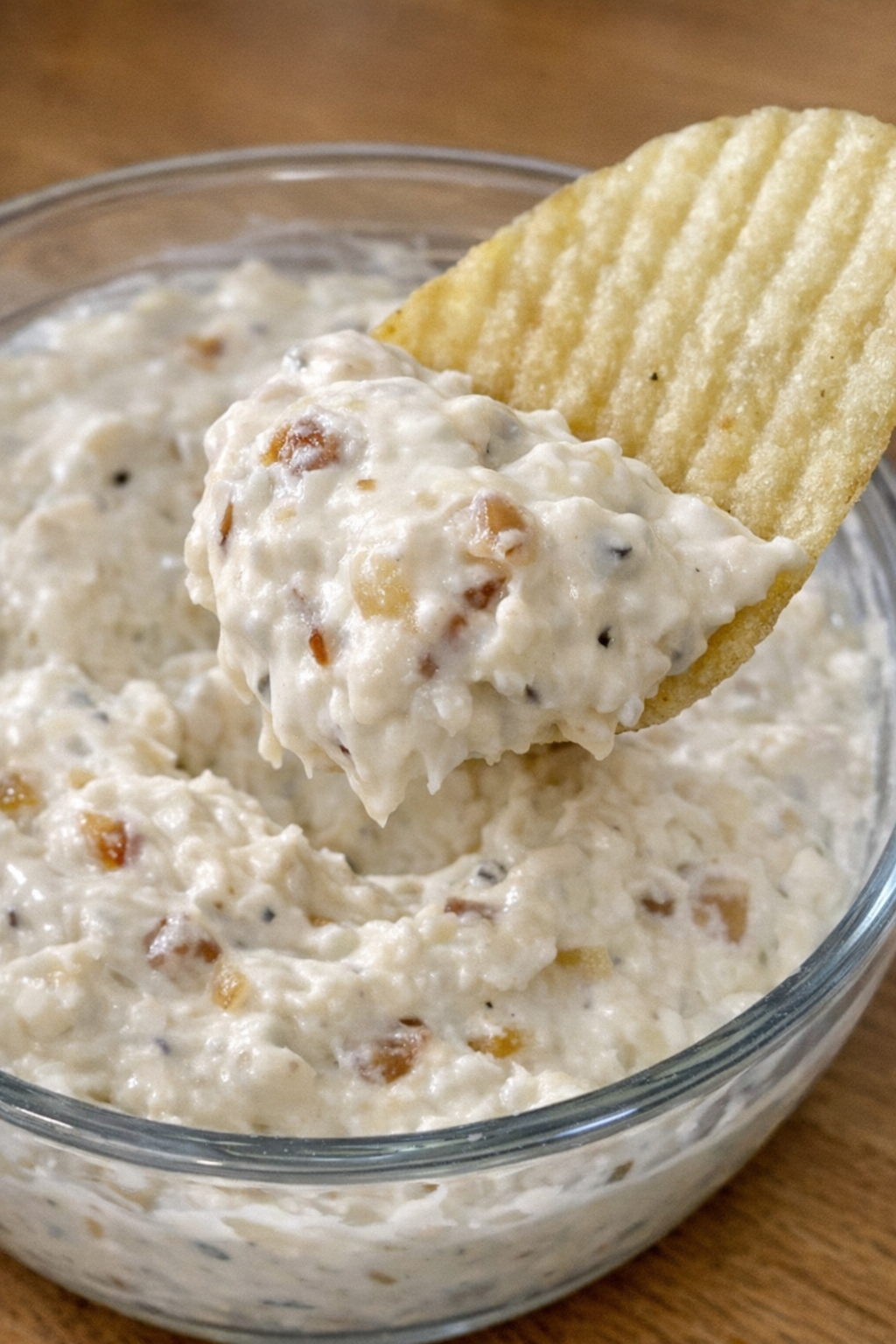 4-ingredient onion merritt dip in a glass bowl with a potato chip scooping it