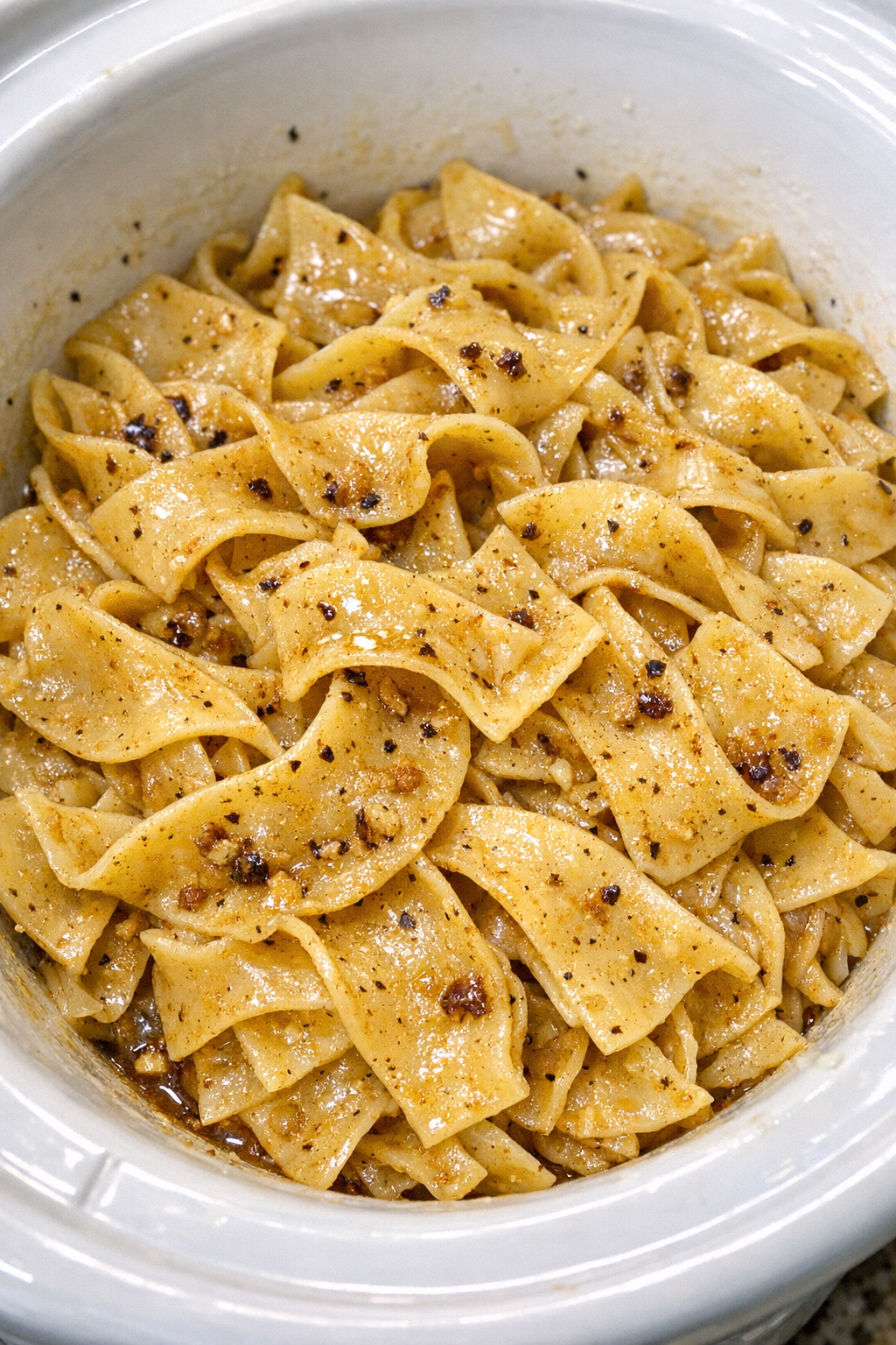Slow cooker Amish brown butter noodles in a white slow cooker
