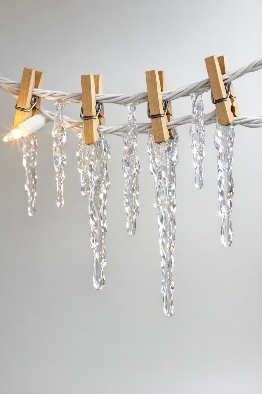 Finished glue icicle bulbs hanging from a clipped light strand while setting