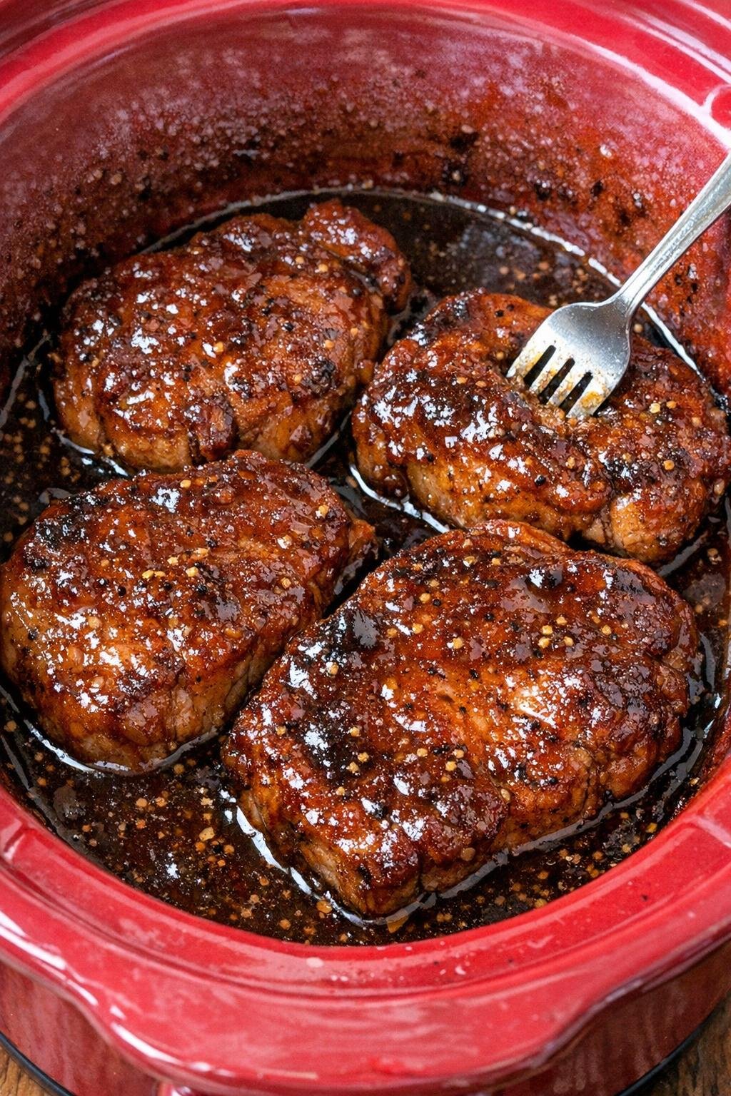 Slow cooker molasses mustard pork chops in a red slow cooker