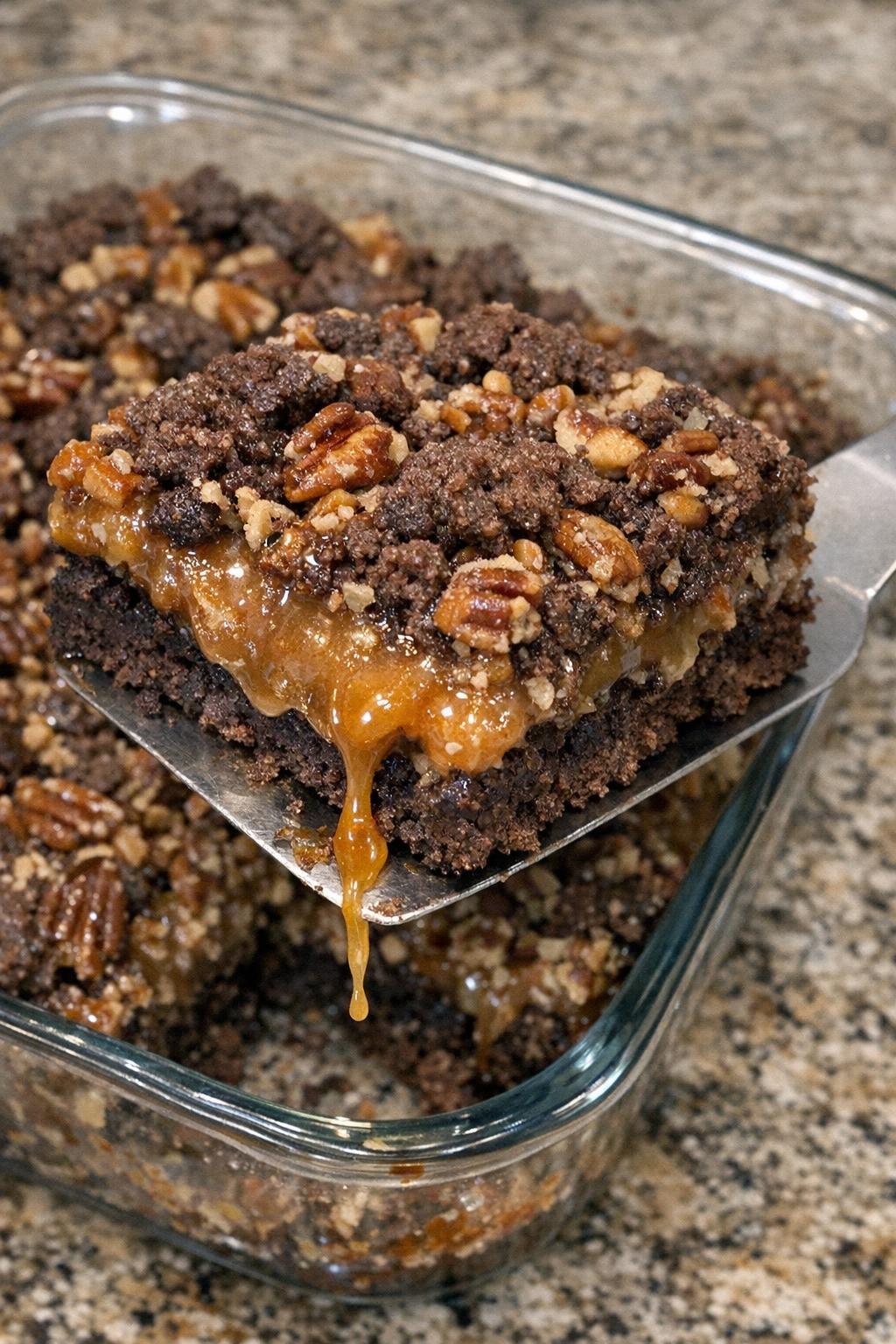 Dark chocolate crumb bars with caramel and pecans in a glass casserole dish
