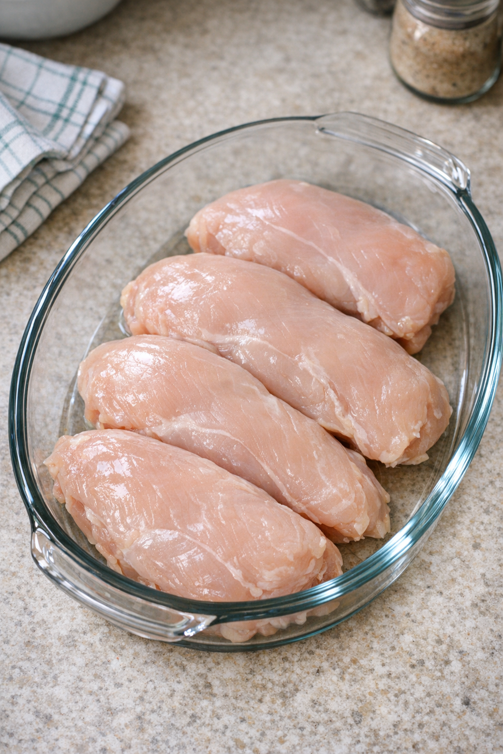 Chicken breasts arranged in a glass baking dish