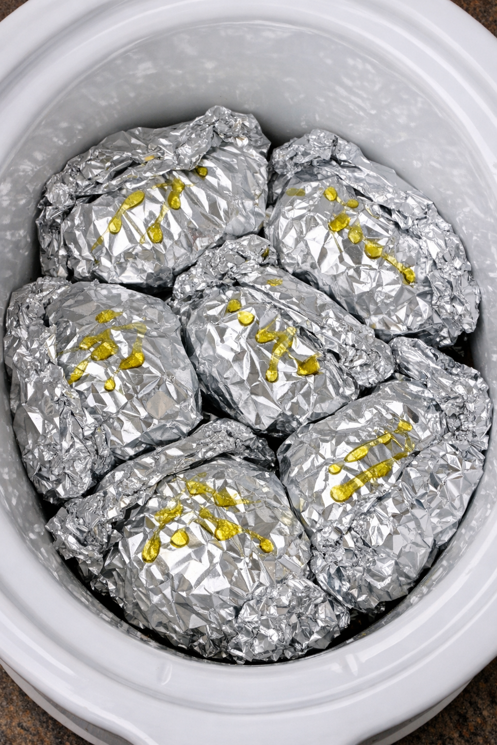 Slow cooker bruschetta chicken foil packets in a white slow cooker