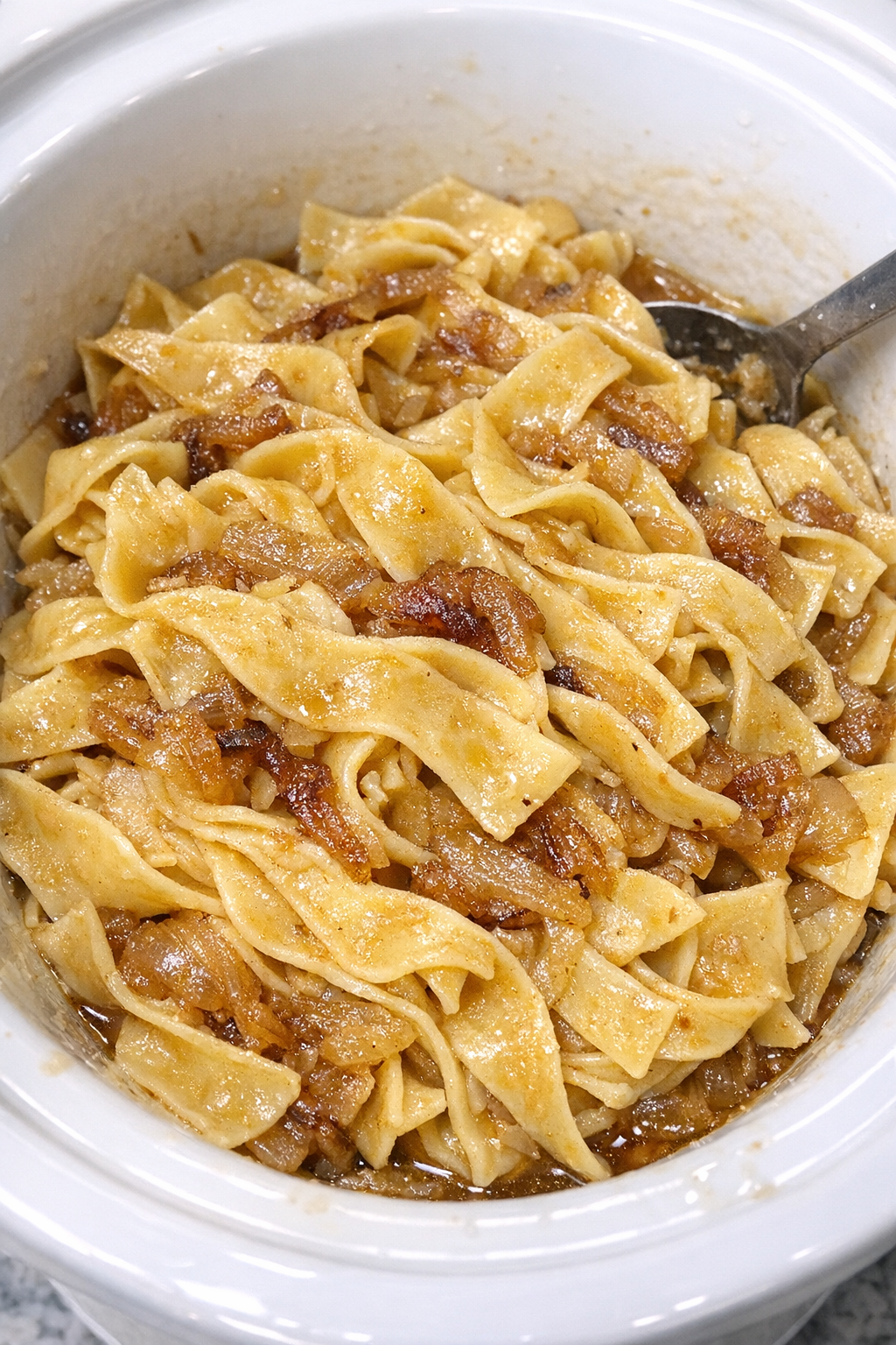 Slow cooker Amish browned onion noodles in a white slow cooker
