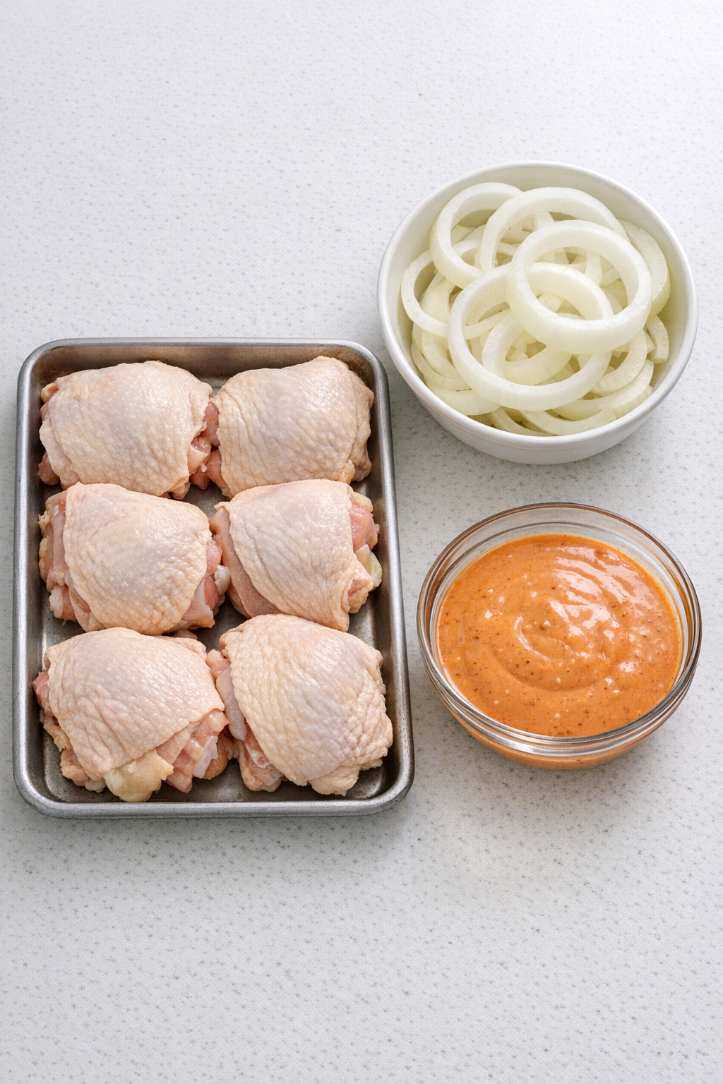 Chicken thighs, sliced sweet onion, and Russian dressing arranged as ingredients