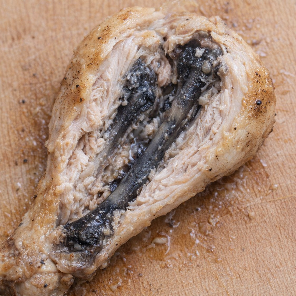 Split chicken drumstick showing dark marrow near the bone