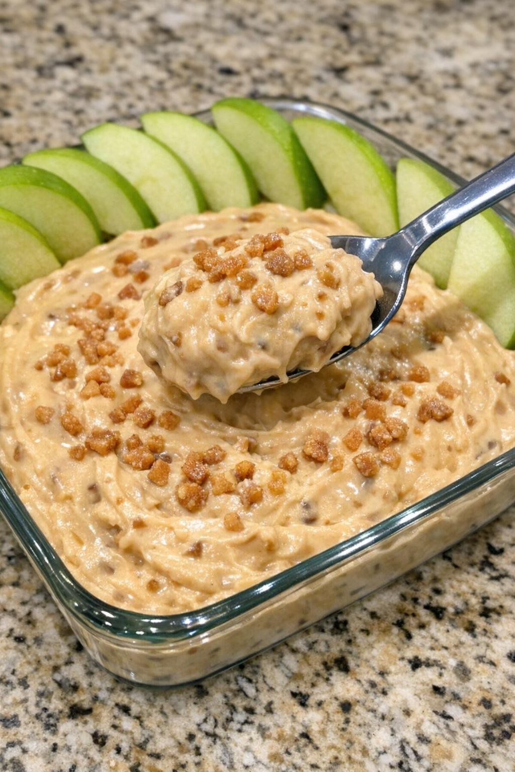 Creamy toffee dip with apple slices in a glass dish