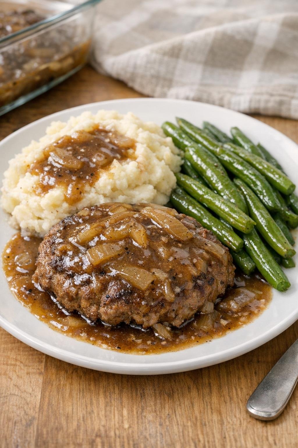 Baked hamburger steaks with onion gravy on a dinner plate