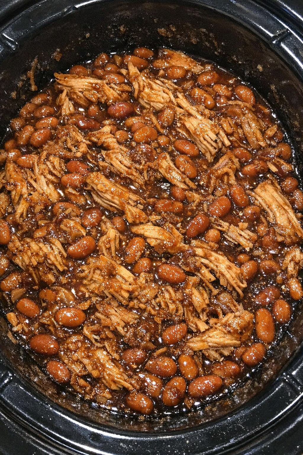 Slow cooker Amish chicken and baked beans in a black slow cooker