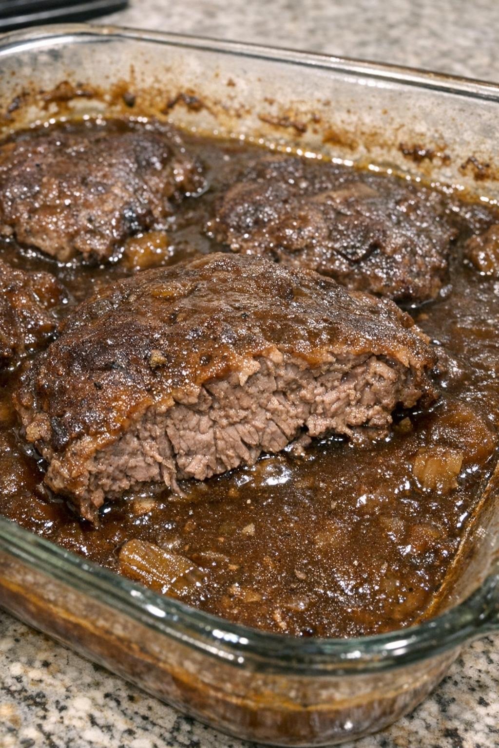 Fork-tender round steak in brown gravy in a glass baking dish