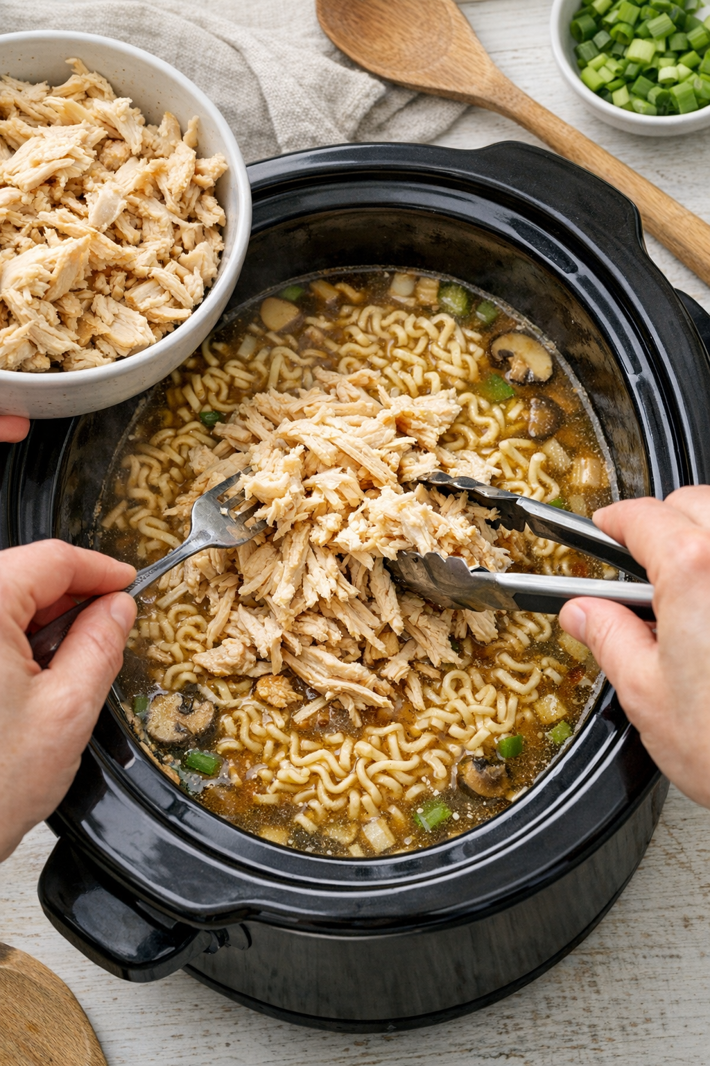 Shredded chicken being returned to the slow cooker