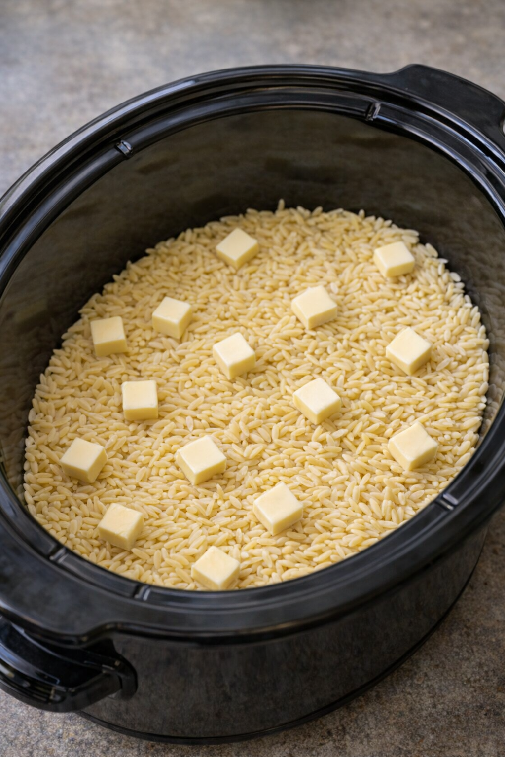 Dry orzo and butter layered in a slow cooker
