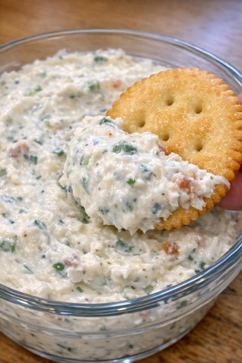 Close-up of ranch Sutton dip in a glass bowl with a cracker scooping