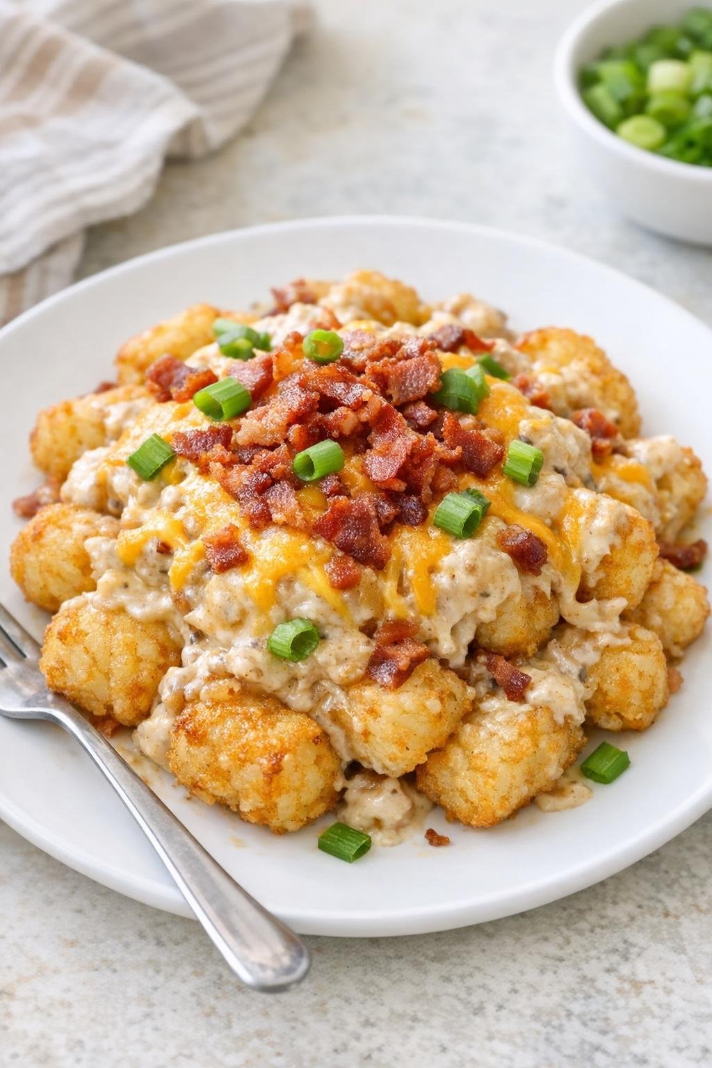 Finished French onion loaded tater tots plated with melted cheese and bacon