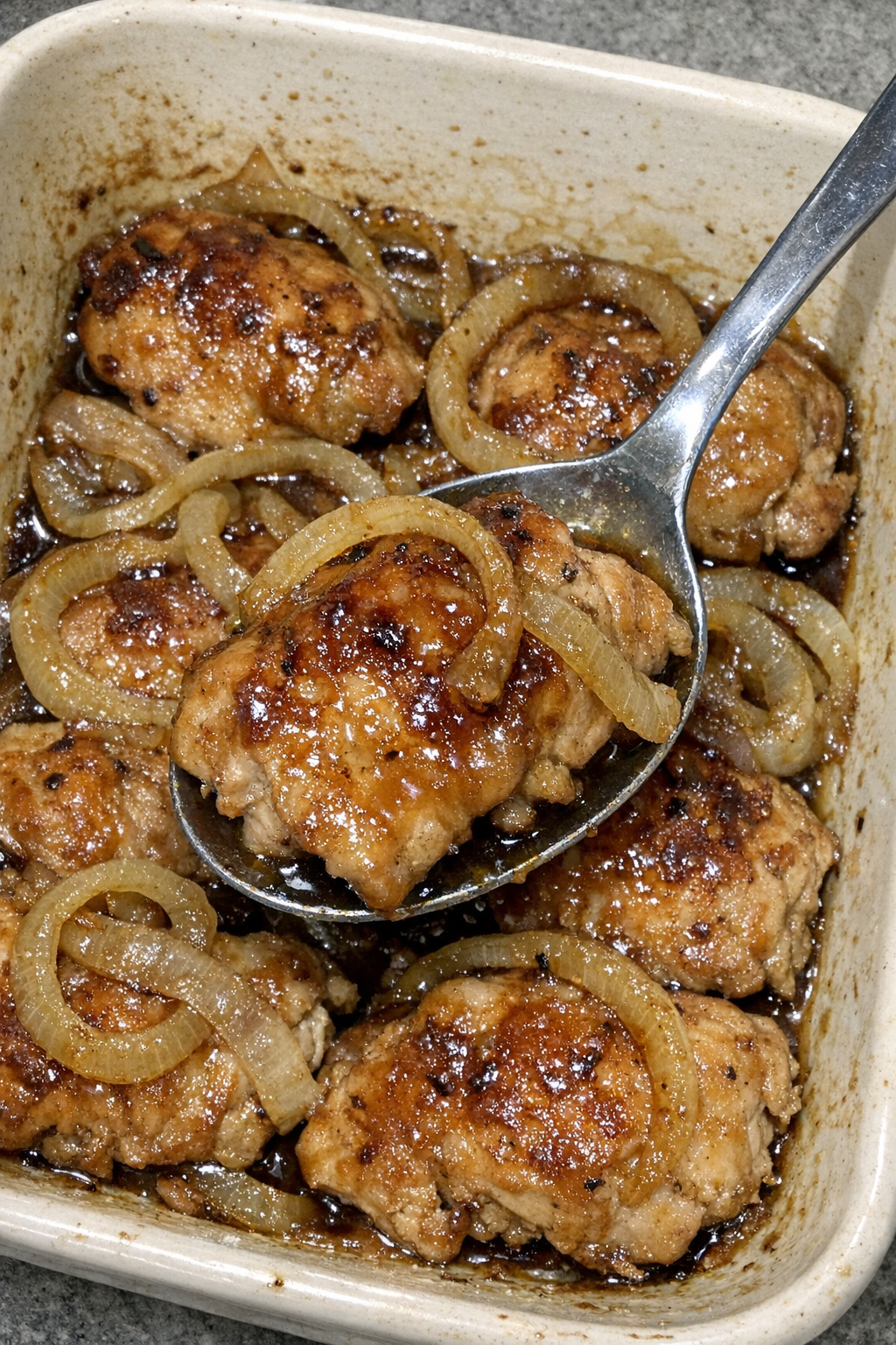 Glazed chicken with caramelized onion rings in a cream casserole dish