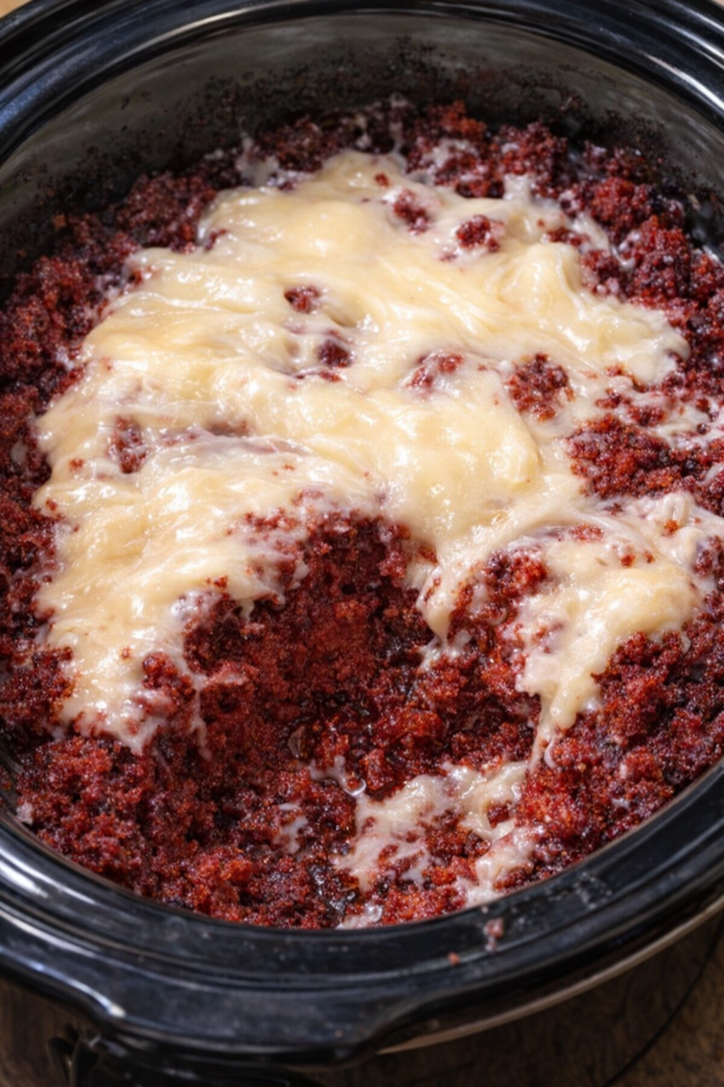 Freshly frosted red velvet dump cake inside the slow cooker