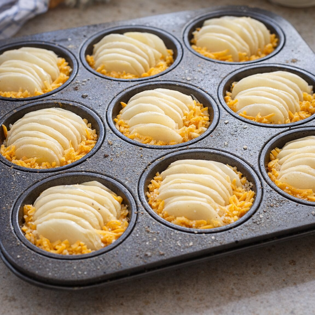 Potato slices layered into muffin cups before baking