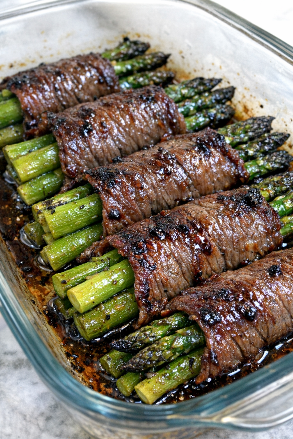 Oven baked beef wrapped asparagus in a glass baking dish