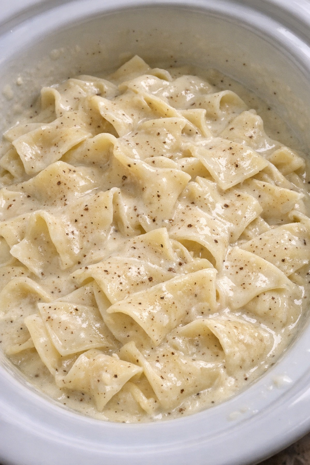 Slow cooker Amish nutmeg cream noodles in a white slow cooker