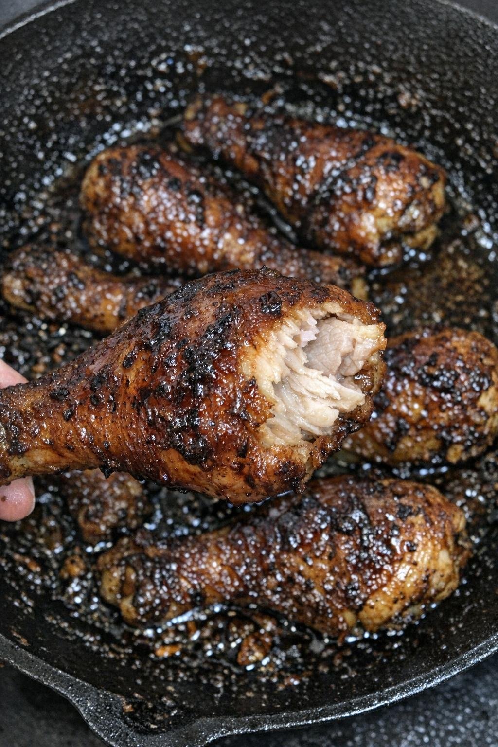 Sticky caramelized chicken drumsticks in a cast iron skillet