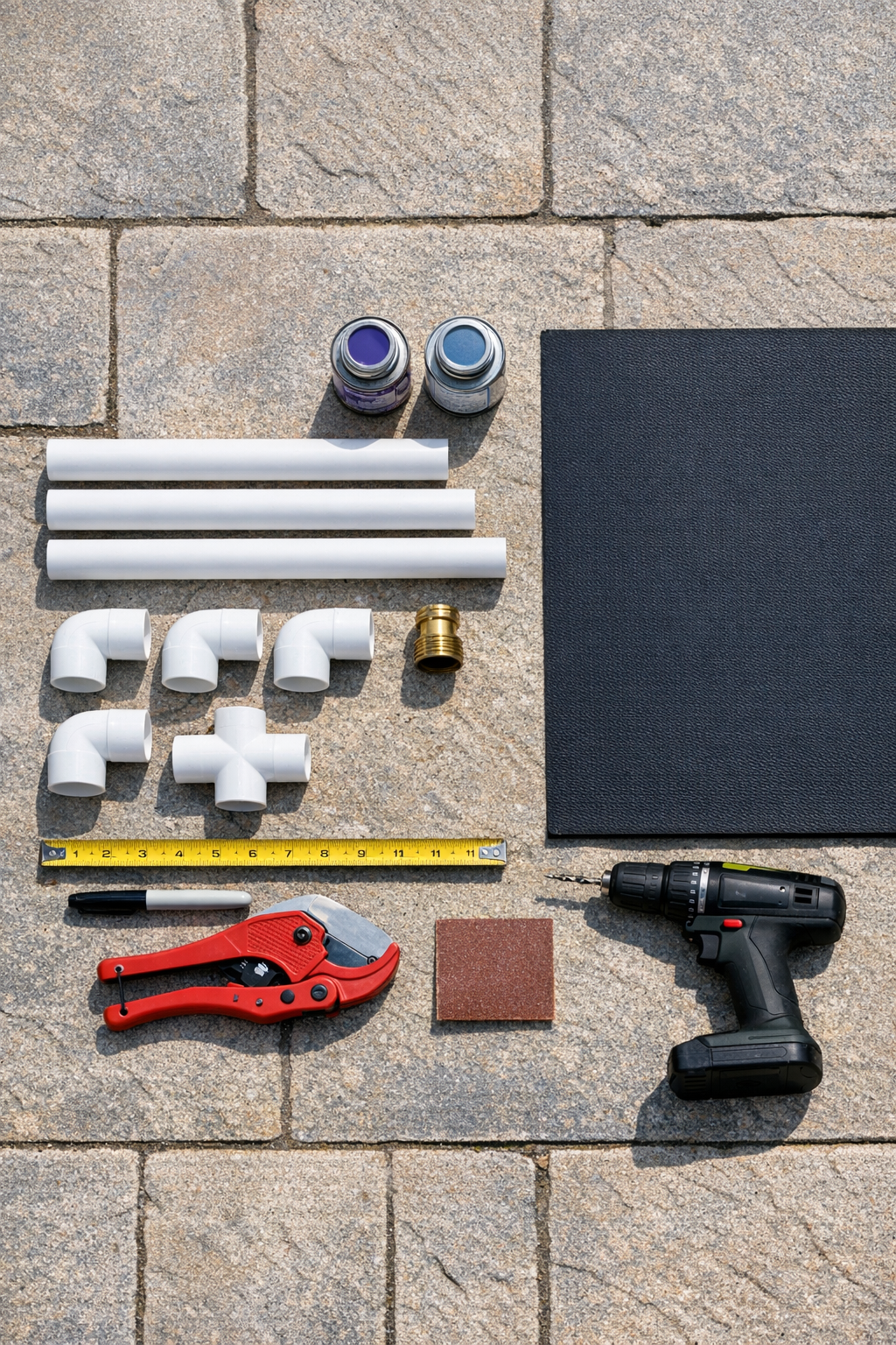 PVC pipe, fittings, hose adapter, rubber mat, and tools laid out for the project
