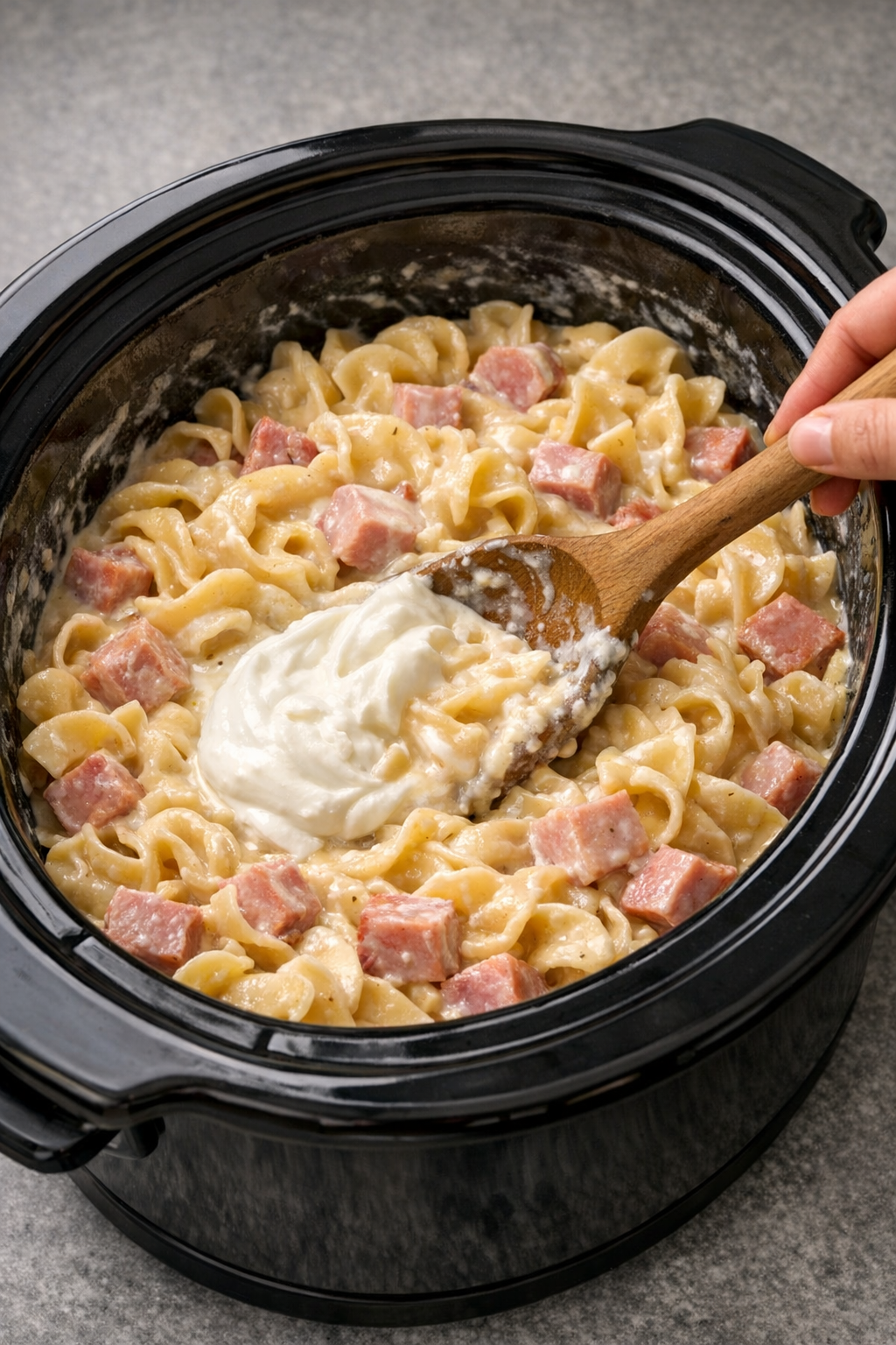 Sour cream being stirred into creamy ham pasta