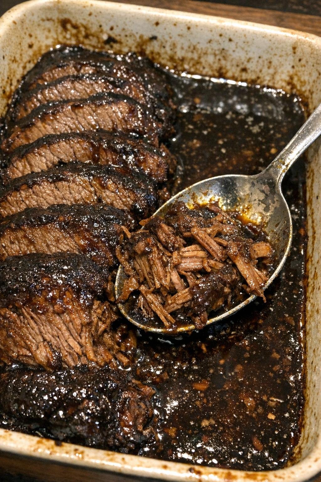 Sliced beef roast with glossy dark glaze in a baking dish