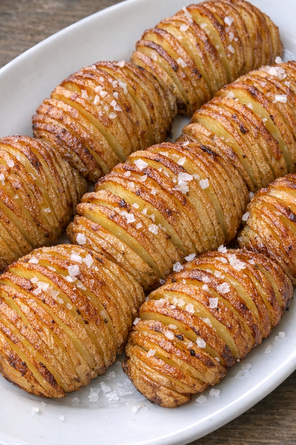 Golden crispy potato fans on a white oval platter