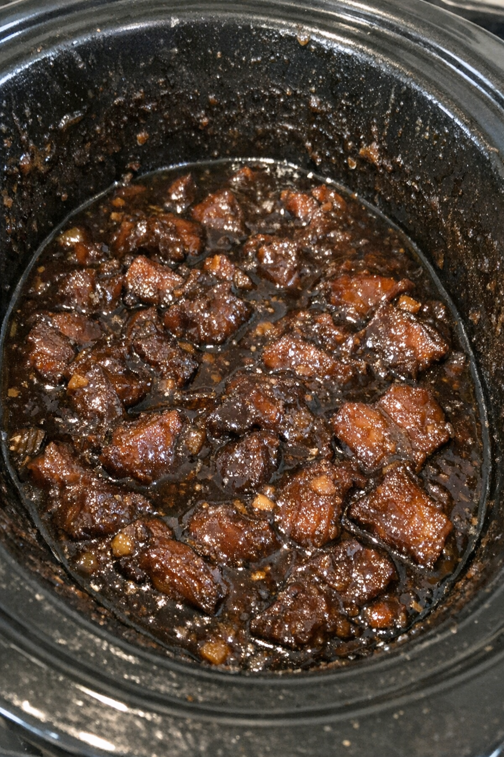 Slow cooker with a dark glossy savory meal