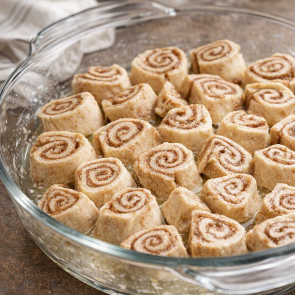 Quartered cinnamon rolls arranged in a baking dish