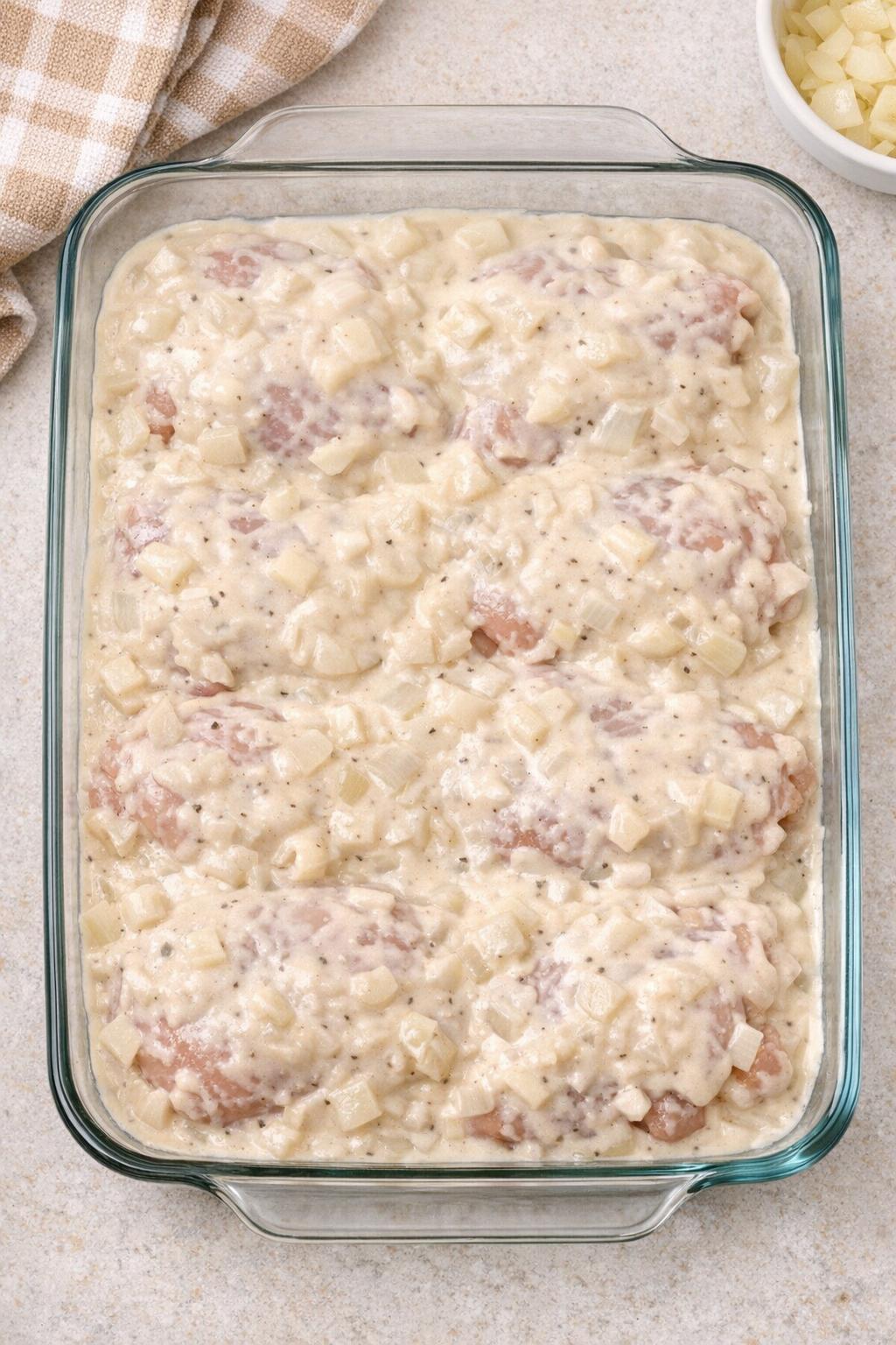 Chicken covered with creamy sauce before baking