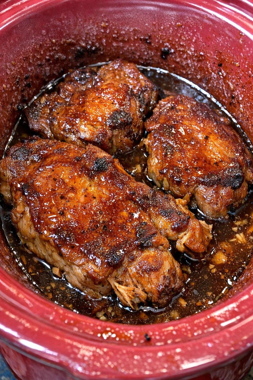 Slow cooker brown sugar apple cider pork chops in a red slow cooker