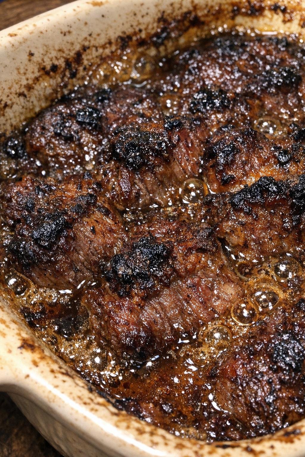 Beef casserole with bubbling savory sauce and caramelized crust in a ceramic baking dish