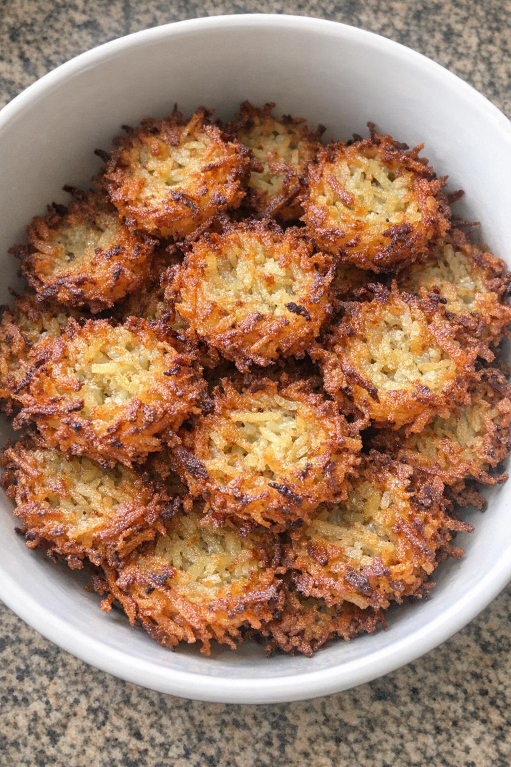 Crispy golden brown shredded potato nests in a white serving bowl